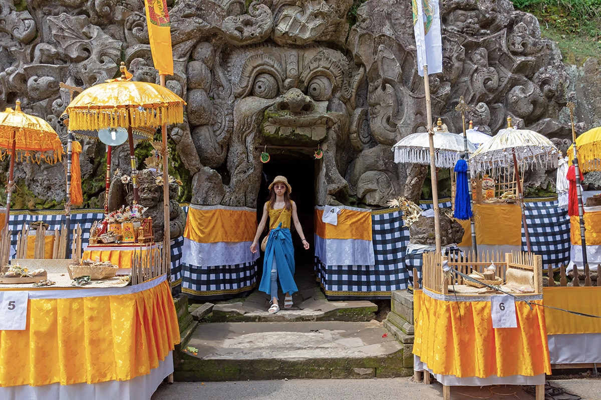 a tourist in a sarong standing close to the entrance of Goa Gajah