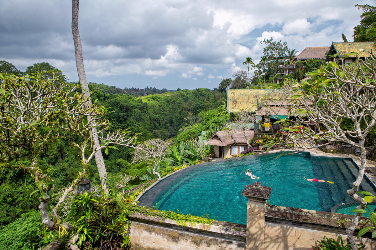 two people swimming in turquoise pool overlooking greenery